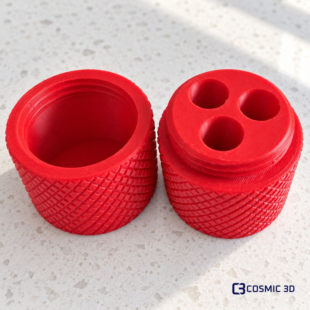 Open red ampoule holder with three fitted openings and its screw-top lid beside it.
