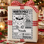 Christmas Pudding North Pole sticker personalised with Noah, shown on a wrapped Christmas gift.